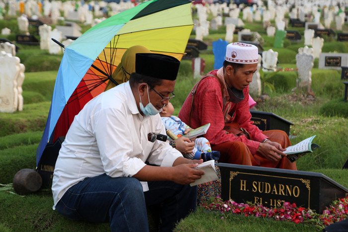 Peziarah berdoa dipisara makam kerabatnya yang dimakamkan di makam khusus Covid-19, Keputih Surabaya, Jawa Timur, Jumat (9/4/2021).