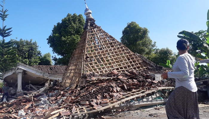 Warga melintas di dekat masjid yang hancur akibat terdampak gempa Malang di Dusun Iburaja, Desa Kaliuling, Kabupaten Lumajang, Jawa Timur, Minggu (11/4/2021).