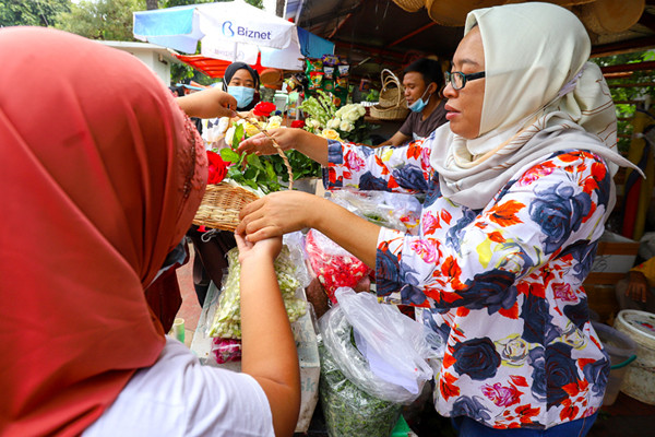 Pedagang bunga tabur melayani warga yang berbelanja bunga dan air mawar di pintu masuk TPU Karet Bivak, Jakarta, Minggu (11/4/2021).