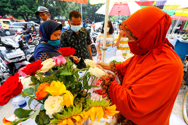 Pedagang bunga tabur melayani warga yang berbelanja bunga dan air mawar di pintu masuk TPU Karet Bivak, Jakarta, Minggu (11/4/2021).