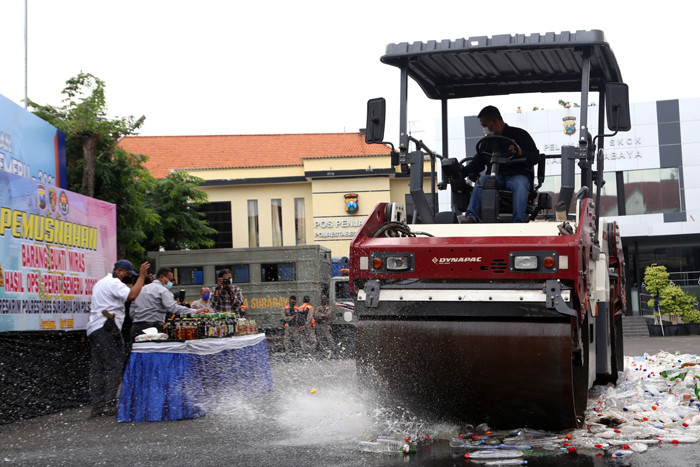 Polisi memusnahkan ribuan barang bukti minuman keras pada hari pertama puasa Ramadan, di halaman Mapolrestabes Surabaya, Jawa Timur, Selasa (13/4/2021).