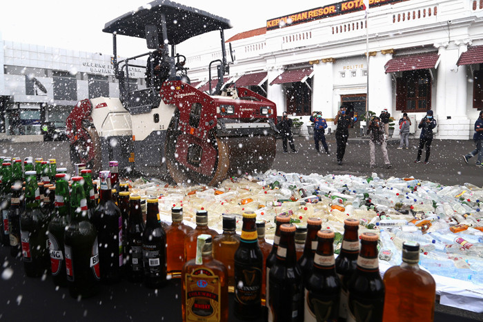Polisi memusnahkan ribuan barang bukti minuman keras pada hari pertama puasa Ramadan, di halaman Mapolrestabes Surabaya, Jawa Timur, Selasa (13/4/2021).
