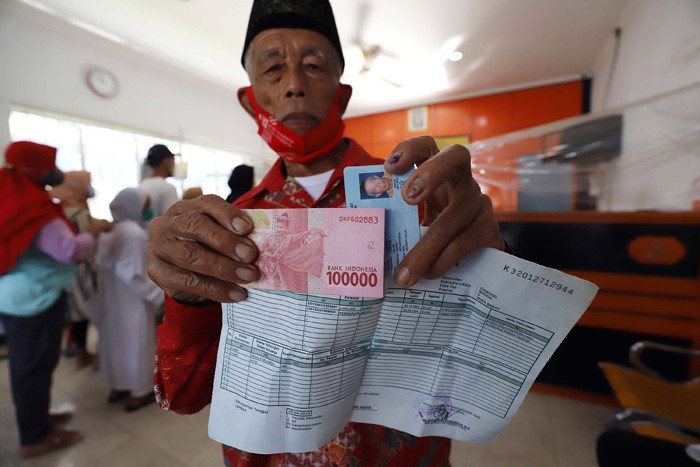 Warga mengantre saat pengambilan Bantuan Sosial Tunai (BST) di Kantor Pos di kawasan Parung, Bogor, Jawa Barat, Rabu (14/4/2021).