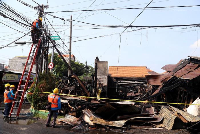 Petugas PLN memperbaiki jaringan listrik yang terputus pasca kebakaran bengkel mebel di Jalan Semolowaru, Surabaya, Kamis (15/4/2021).