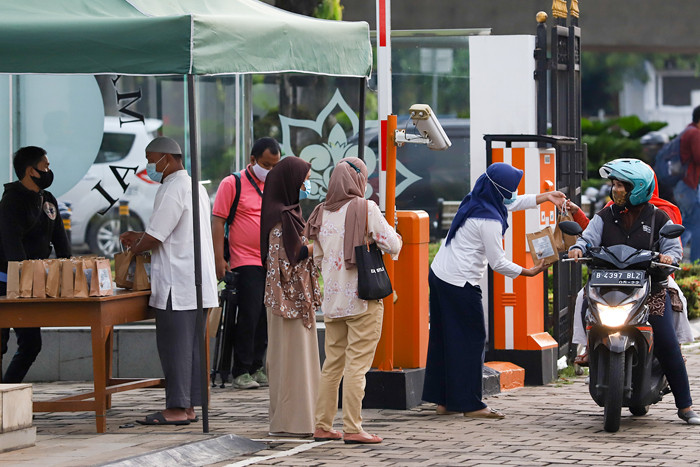 Pengurus masjid membagikan takjil gratis di halaman Masjid Al-Azhar, Jakarta, Kamis (15/4/2021).