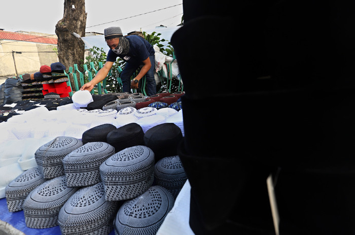 Penjual merapikan peci di kawasan Cillitan, Jakarta Timur, Selasa (20/4/2021).