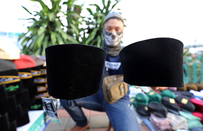 Penjual merapikan peci di kawasan Cillitan, Jakarta Timur, Selasa (20/4/2021).