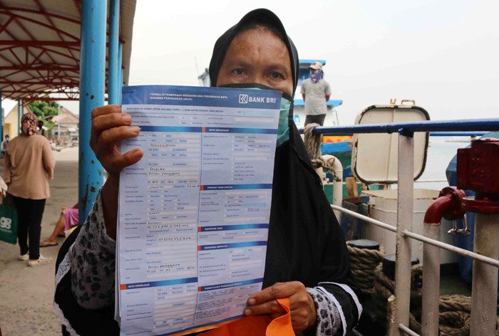 Warga antre untuk mencairkan dana bantuan UMKM di Dermaga Pelabuhan Pulau Panggang, Kepulauan Seribu Utara, Provinsi DKI Jakarta, Selasa (20/4/2021).