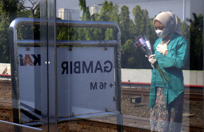 Petugas KAI dengan mengenakan pakaian kebaya memberikan bunga kepada penumpang di Stasiun Gambir, Jakarta, Rabu (21/4/2021).