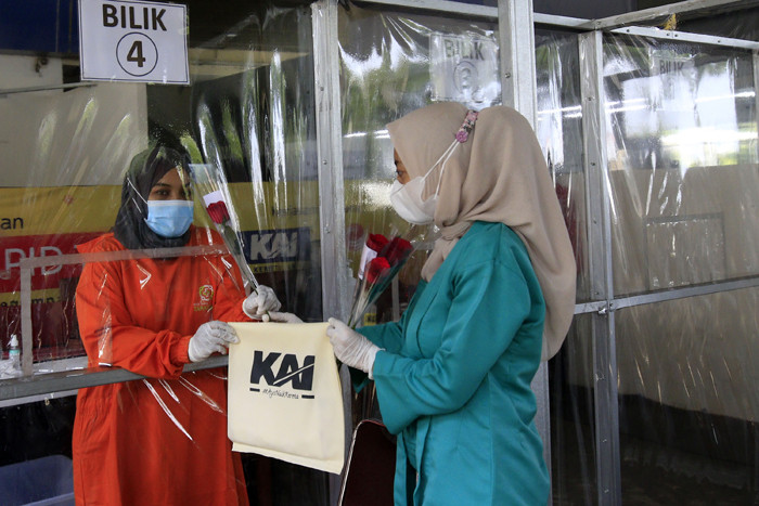 Petugas KAI dengan mengenakan pakaian kebaya memberikan bunga kepada penumpang di Stasiun Gambir, Jakarta, Rabu (21/4/2021).