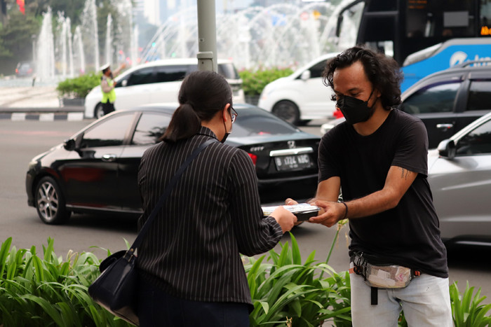 Pewarta Foto membagikan takjil kepada pejalan kaki di Kawasan Bundaran HI, Jakarta, Jumat (23/4/2021).