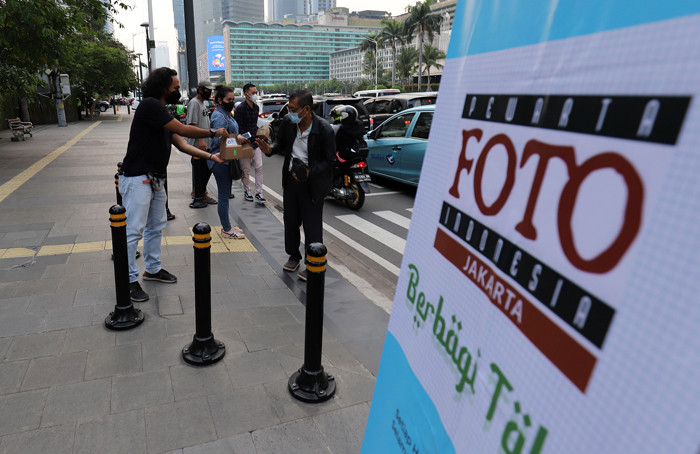 Pewarta Foto membagikan takjil kepada pejalan kaki di Kawasan Bundaran HI, Jakarta, Jumat (23/4/2021).