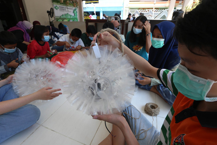Sejumlah anak belajar membuat lampu gantung berbahan gelas air mineral bekas di Kampung Herbal, Surabaya, Jawa Timur, Sabtu (24/4/2021).