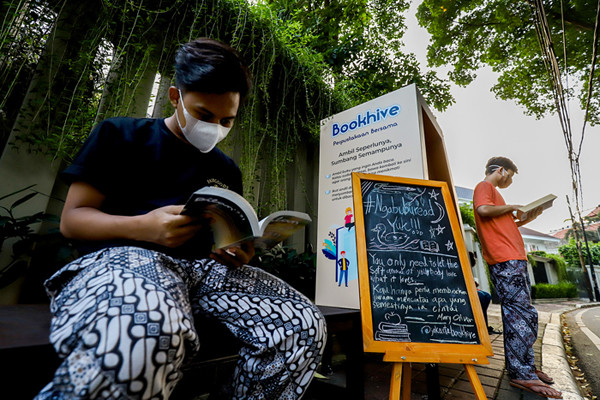 Warga membaca buku di rak buku Bookhive di kawasan Taman Situ Lembang, Menteng, Jakarta Pusat, Senin (26/4/2021).