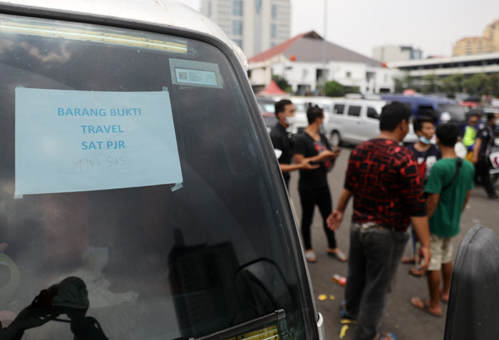Petugas kepolisian memeriksa barang bukti kendaraan travel gelap di Lapangan Presisi Dit Lantas PMJ, Jakarta, Kamis (29/4/2021).