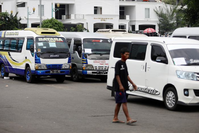 Petugas kepolisian memeriksa barang bukti kendaraan travel gelap di Lapangan Presisi Dit Lantas PMJ, Jakarta, Kamis (29/4/2021).