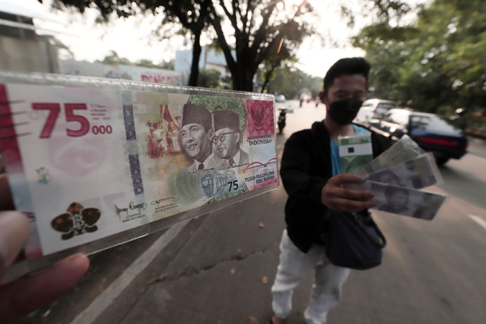 Penjual jasa penukaran uang menawarkan uang baru Rp75 ribu di kawasan Taman Mini Indonesia Indah, Jakarta Timur, Jumat (30/4/2021).