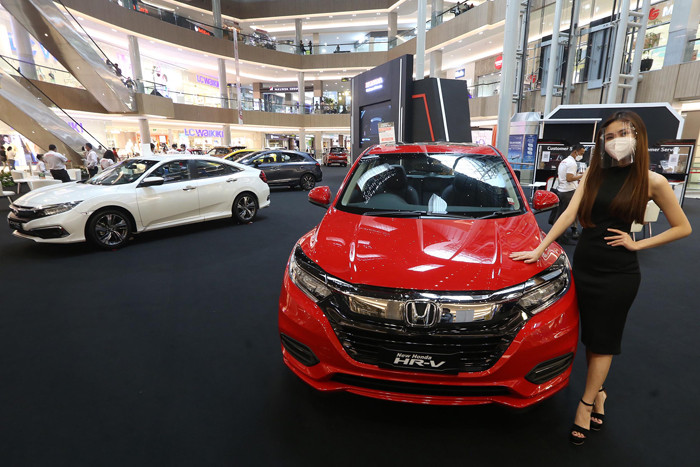 Sales Promotion Girl (SPG) berpose disisi unit mobil Honda saat pameran di Grand Atrium Pakuwon Mall Surabaya,  Jawa Timur, Jumat (30/4/2021).