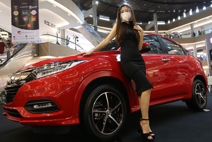 Sales Promotion Girl (SPG) berpose disisi unit mobil Honda saat pameran di Grand Atrium Pakuwon Mall Surabaya,  Jawa Timur, Jumat (30/4/2021).