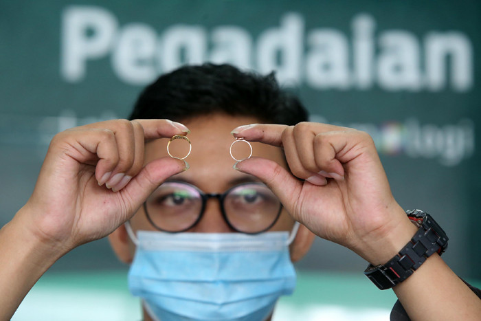 Petugas Pegadaian memeriksa cincin emas milik calon nasabah di Pegadaian Dinoyo, Surabaya, Jawa Timur, Jumat (30/4/2021).