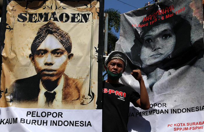 Buruh membentangkan poster bergambar Semaoen dan Marsinah saat aksi May Day didepan kantor Disnakertrans Provinsi Jawa Timur, Sabtu (1/5/2021).