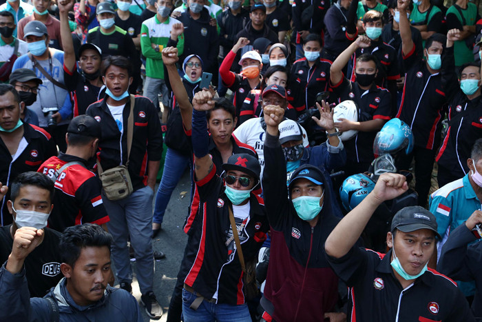 Buruh membentangkan poster bergambar Semaoen dan Marsinah saat aksi May Day didepan kantor Disnakertrans Provinsi Jawa Timur, Sabtu (1/5/2021).