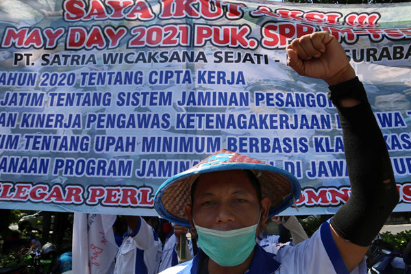 Buruh membentangkan poster bergambar Semaoen dan Marsinah saat aksi May Day didepan kantor Disnakertrans Provinsi Jawa Timur, Sabtu (1/5/2021).