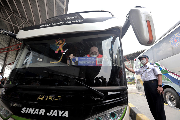 Petugas memasang stiker khusus pada armada bus yang diperbolehkan beroperasi saat masa larangan arus mudik di Terminal Pulo Gebang, Jakarta, Selasa (4/5/2021).