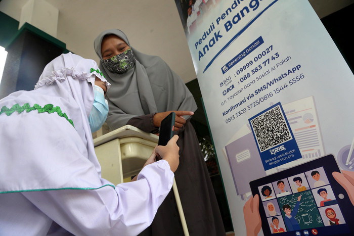 Siswa SD Al Falah Surabaya melakukan Scan QRIS ketika membayar infaq dan sedekah Ramadan di SD Al Falah Surabaya, Jawa Timur, Rabu (5/5/2021).