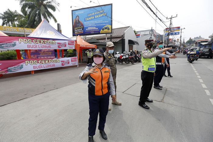 Petugas gabungan mengatur lalu lintas hari pertama penyekatan larangan mudik di perbatasan Jakarta-Tangerang di Jalan Ciledug Raya, Jakarta, Kamis (6/5/2021).