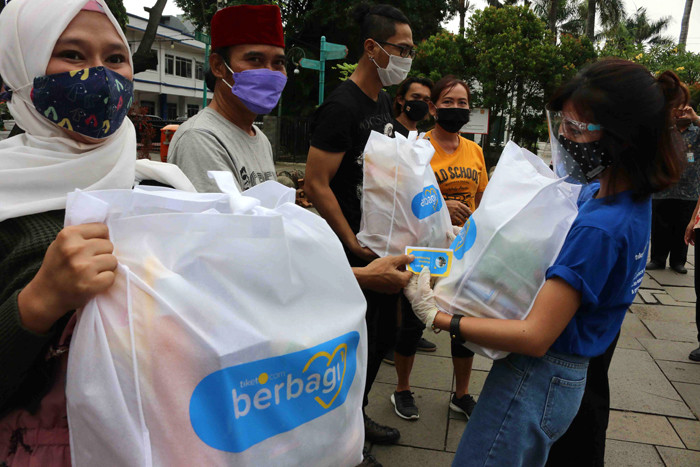 Tiket.com membagikan paket sembako di kawasan Kota Tua, Jakarta. Kamis (6/5/2021).