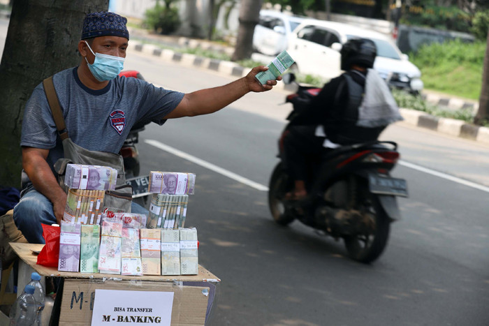Siregar (44) menawarkan uang baru dalam berbagai pecahan di kawasan Pondok Indah, Jakarta, Jumat (7/5/2021).