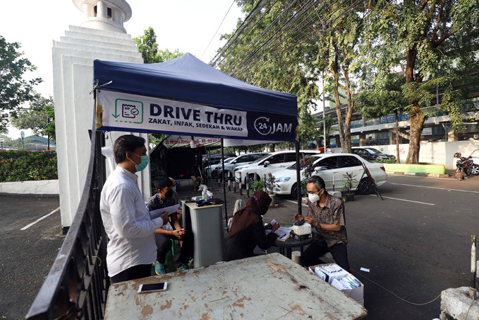 Warga membayar zakat di tenda pelayanan penyaluran zakat fitrah di Masjid Al-Azhar, Jakarta, Jumat (7/5/2021).
