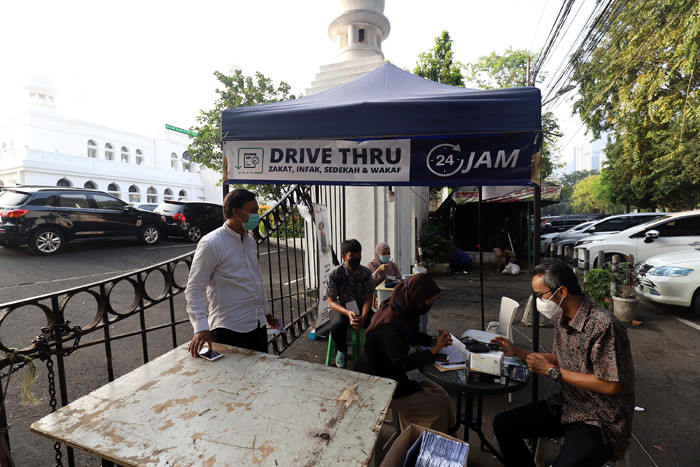 Warga membayar zakat di tenda pelayanan penyaluran zakat fitrah di Masjid Al-Azhar, Jakarta, Jumat (7/5/2021).