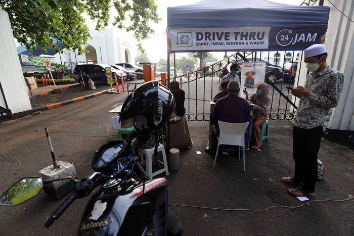 Warga membayar zakat di tenda pelayanan penyaluran zakat fitrah di Masjid Al-Azhar, Jakarta, Jumat (7/5/2021).