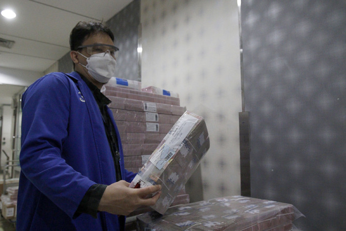 Karyawan sedang merapikan tumpukan uang tunai pecahan kecil dan besar di cash pooling Bank Mandiri, Jakarta, Jumat (7/5/2021).