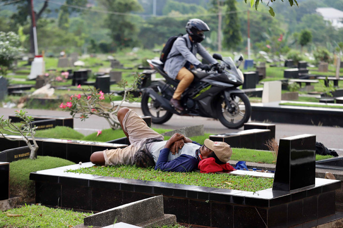Pekerja makam tidur diatas makam di TPU Tanah Kusir, Jakarta, Selasa (11/5/2021).
