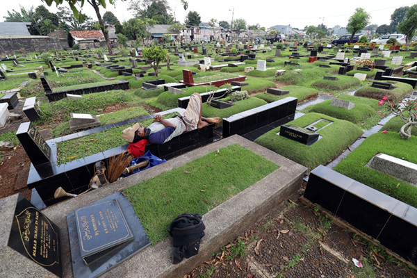 Pekerja makam tidur diatas makam di TPU Tanah Kusir, Jakarta, Selasa (11/5/2021).