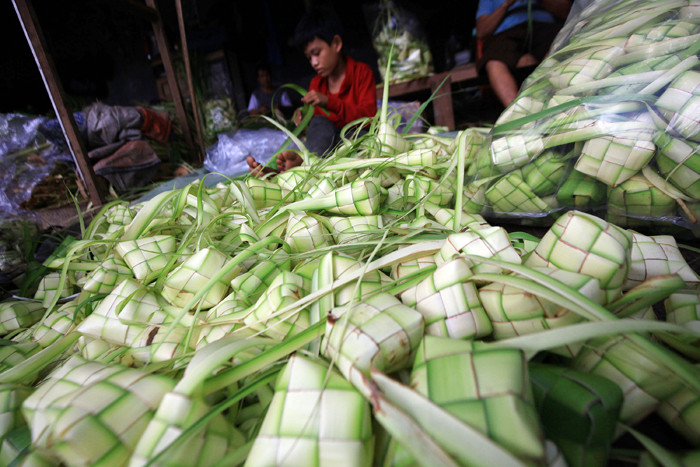 Pedagang menyelesaikan pembuatan kulit ketupat yang dijual di kawasan Palmerah, Jakarta, Rabu (12/5/2021).