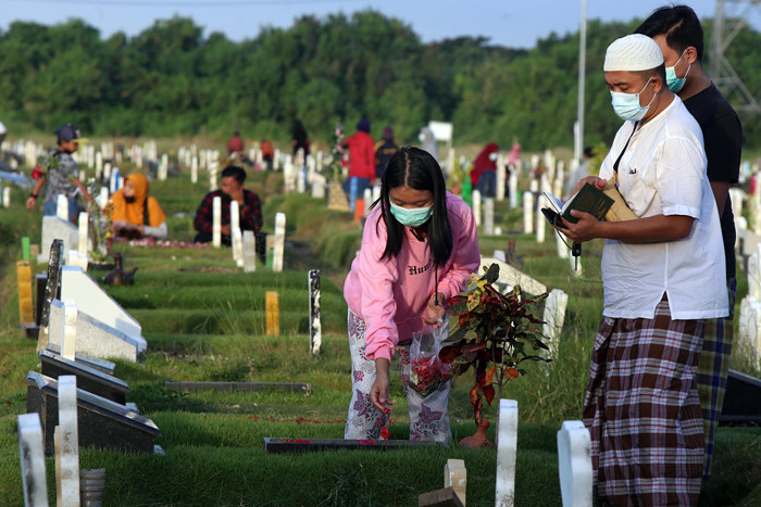 Kerabat korban Covid-19 membaca ayat-ayat suci Alquran dan berdoa ketika berziarah di makam khusus Covid-19, Keputih Surabaya, Jawa Timur, Rabu (12/5/2021).