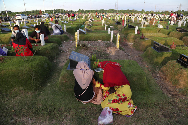 Kerabat korban Covid-19 membaca ayat-ayat suci Alquran dan berdoa ketika berziarah di makam khusus Covid-19, Keputih Surabaya, Jawa Timur, Rabu (12/5/2021).