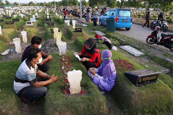 Kerabat korban Covid-19 membaca ayat-ayat suci Alquran dan berdoa ketika berziarah di makam khusus Covid-19, Keputih Surabaya, Jawa Timur, Rabu (12/5/2021).