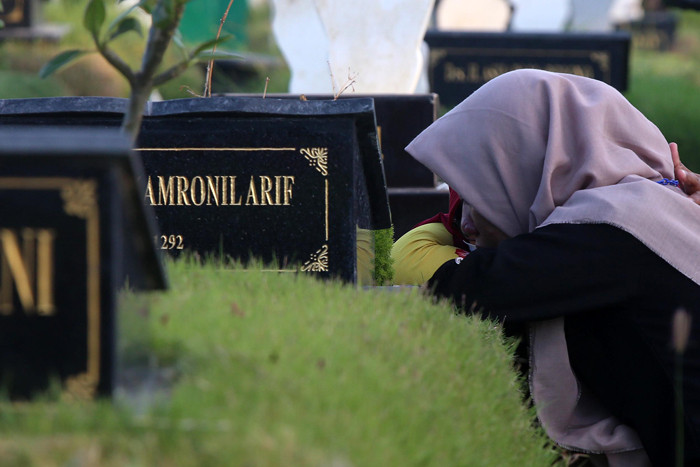 Kerabat korban Covid-19 membaca ayat-ayat suci Alquran dan berdoa ketika berziarah di makam khusus Covid-19, Keputih Surabaya, Jawa Timur, Rabu (12/5/2021).