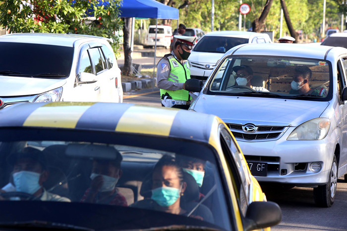 Petugas memberhentikan dan memeriksa dokumen perjalanan pengendara saat melintas di pos penyekatan pintu masuk Jembatan Suramadu, Jawa Timur, Rabu (12/5/2021).