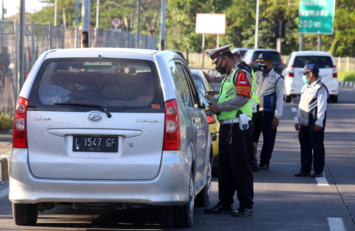 Petugas memberhentikan dan memeriksa dokumen perjalanan pengendara saat melintas di pos penyekatan pintu masuk Jembatan Suramadu, Jawa Timur, Rabu (12/5/2021).