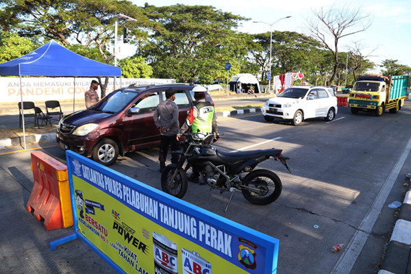 Petugas memberhentikan dan memeriksa dokumen perjalanan pengendara saat melintas di pos penyekatan pintu masuk Jembatan Suramadu, Jawa Timur, Rabu (12/5/2021).
