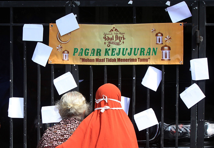 Puluhan anak dan warga mengambil amplop lebaran di Pagar Kejujuran di kediaman keluarga Trisnadi Marjan di Sidoarjo, Jawa Timur, Kamis (13/5/2021).