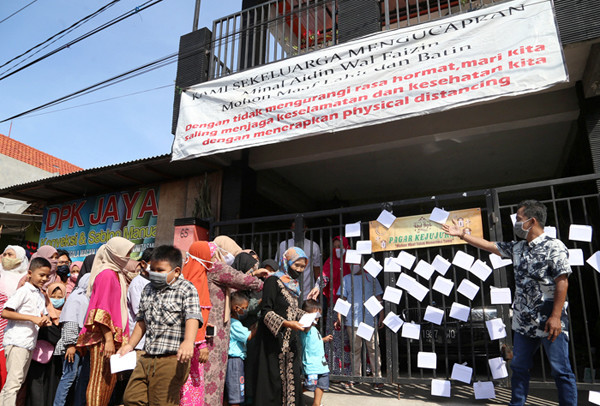 Puluhan anak dan warga mengambil amplop lebaran di Pagar Kejujuran di kediaman keluarga Trisnadi Marjan di Sidoarjo, Jawa Timur, Kamis (13/5/2021).