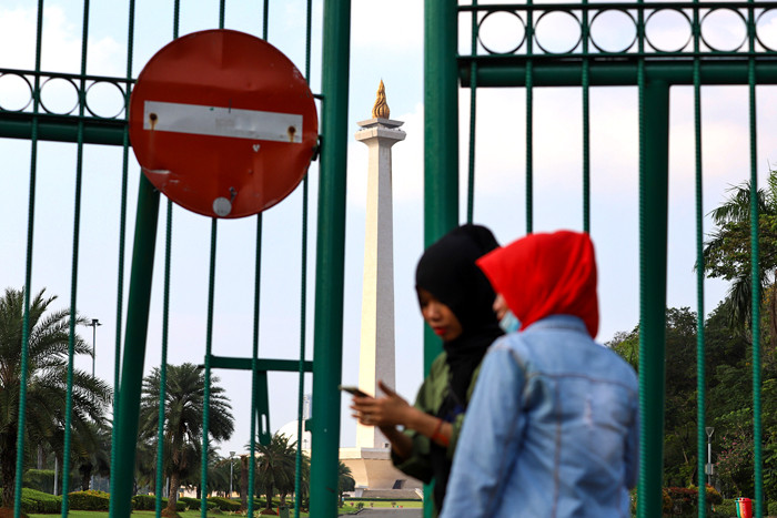 Warga di luar pagar Monumen Nasional (Monas) yang tutup di Jakarta Pusat, Sabtu (15/5/2021).