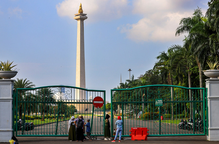Warga di luar pagar Monumen Nasional (Monas) yang tutup di Jakarta Pusat, Sabtu (15/5/2021).